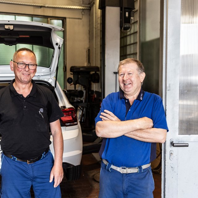 Zwei Mitarbeiter von Autohaus Biggel vor einem weißen Auto