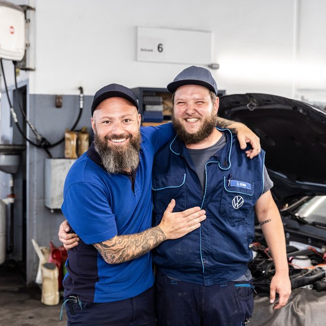 Zwei Mitarbeiter von Autohaus Biggel stehen vor einem Auto in der Werkstatt
