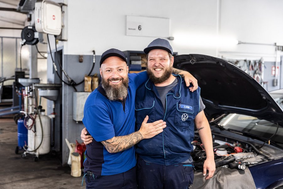 Zwei Mitarbeiter von Autohaus Biggel stehen vor einem Auto in der Werkstatt