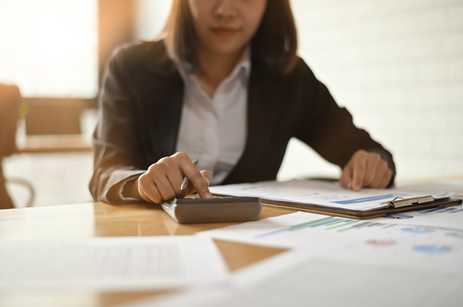 Büroarbeit Person arbeitet mit Dokumenten in einer Büroumgebung, fokussiert auf Planung und Analyse.