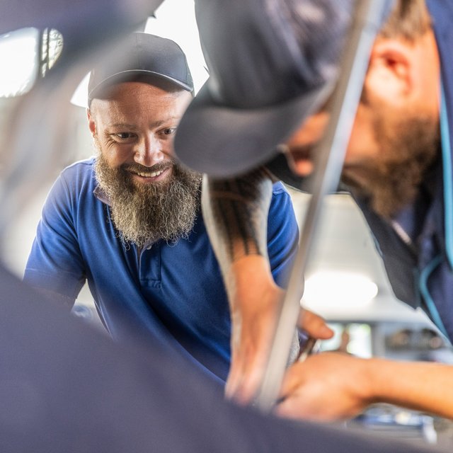 Zwei Werkstattmitarbeiter von Autohaus Biggel arbeiten an einem Auto