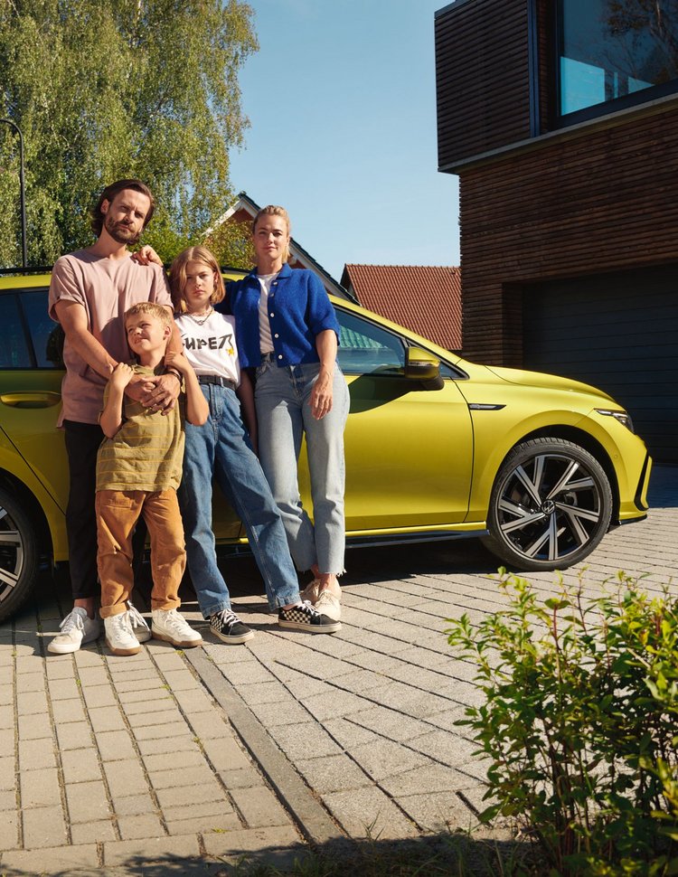 Eine Familie steht vor einem VW Golf