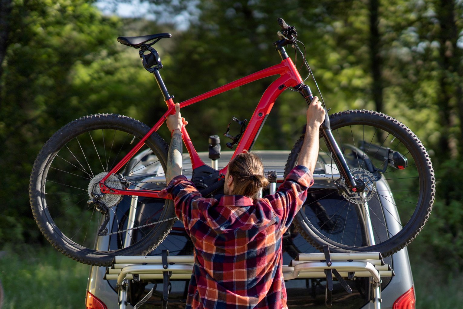 Mann befestigt Fahrrad an Autoträger